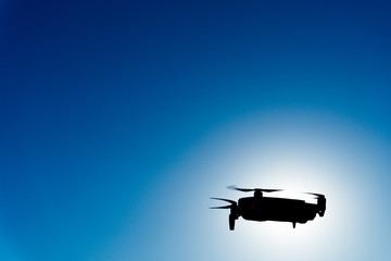 Generic image of a white drone flying across a blue sky. Remote control equipment for aerial...