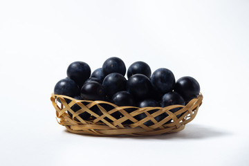 Plum in a wicker basket. Photo on a white background. Summer harvest