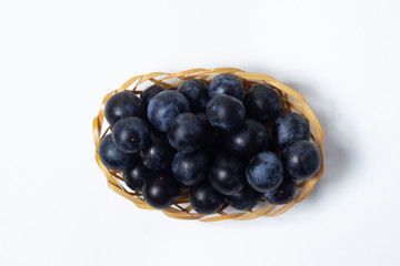Plum in a wicker basket. Photo on a white background. Summer harvest