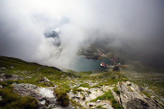 alea Lake covered by fog, Fagaras Mountains, Romania in the summer.