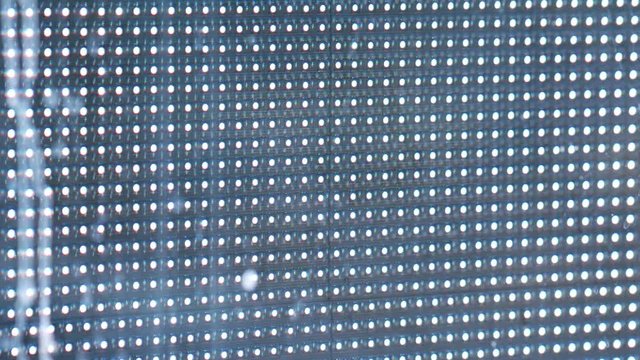Bright colored RGB led dots on a black advertising panel close. Close-up of blocks of LED street display. Glare from neon advertisements. Animated ads are played on outdoor signboards. Macro details