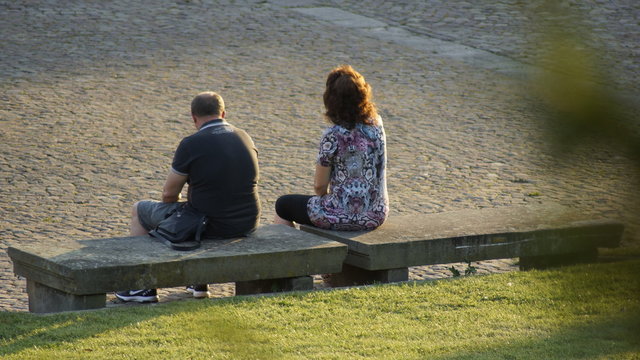 Mann und Frau auf Parkbank sitzend. R&uuml;ckansicht.