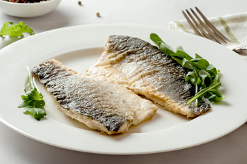 Sea bass fillet fried on a plate, seafood.