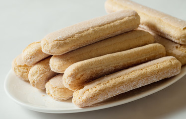 Ladies fingers cookies on a plate with powdered sugar, savoiardi.