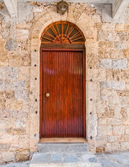 Fototapeta na wymiar stone wall house natural wooden arched door by the sidewalk