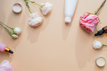 Cosmetics from natural ingredients and extracts of flowers and roses on a beige background. Cream, lotion, gel in white tubes with mock up