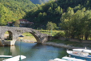 Fototapeta na wymiar View of the bridge over the river with a round span, built of stone, an old building in Montenegro