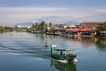 Fototapeta na wymiar Thu bon river and boat in citycentre of Hoi An, Vietnam, mountain background