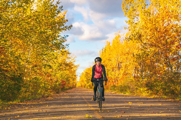 Bike autumn ride woman biking outdoors in fall nature foliage park - bicycle tourism active leisure recreational activity lifestyle people. Girl cyclist.