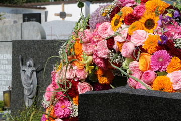 Bunter Blumenkranz an einem Friedhof nach der Beisetzung, Floristik, Grabpflege, Todesfall