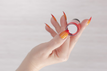 Female hand with long nails and yellow, orange and red gradient manicure holds a bottle of nail polish © Kozlik_mozlik