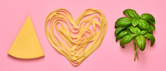Basil, parmesan cheese, pasta. Vegan food, creative composition on pink. Fresh basil, cheese layout, macaroni heart. Cooking minimal. Italian pasta love concept, top view.