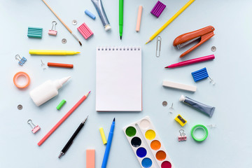 Colored different school supplies on soft blue paper background. Notebook, pens, pencils and other tools. Back to school background. Mock up
