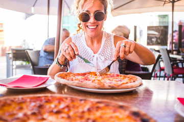Happy young adult caucasian woman ready to eat a beautiful and tasty healthy pizza at the...