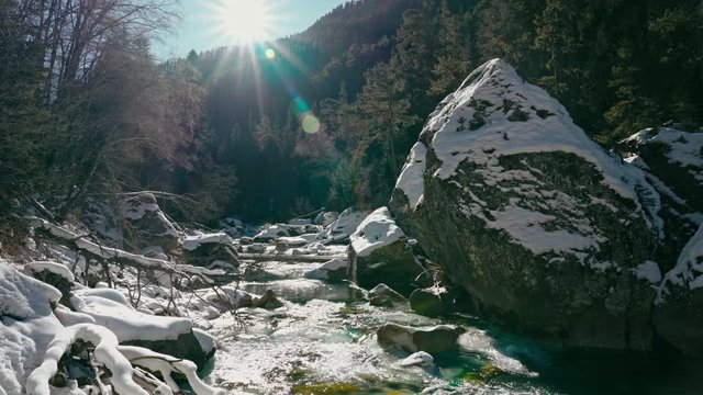 Mountain river in a green forest with snow, Sunny and blue sky