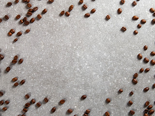 Coffee beans are scattered on a stone table, background. Copy space.