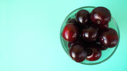red juicy cherry in a clear glass glass on a blue background top view . ripe summer berries