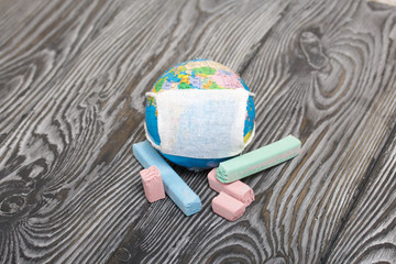 Globe with medical mask. Nearby are crayons. Academic year during the epidemic.