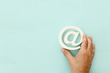 man holding email sign against blue pastel background