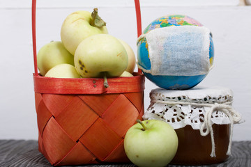 Apples in a red wicker basket. Jam in jars and apples nearby. Fruit harvest. Nearby is a globe with a medical mask.