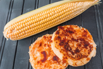 Corn arepas next to an ear of corn. Colombian cuisine