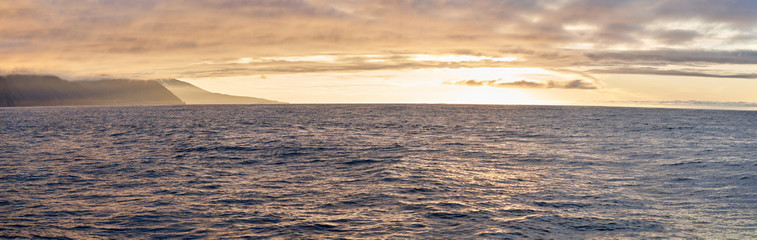 Beautiful panoramic view of a sunset on the atlantic ocean near the coast of husavik in iceland