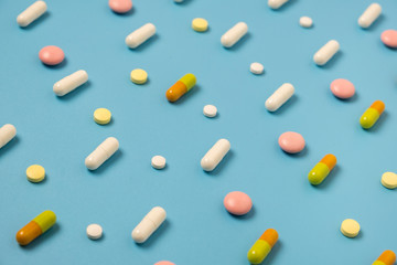 Close up of many different pills arranged in pattern on blue background.