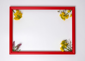 Red wooden picture frame decorated with small yellow flowers on white background.
