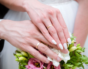 Obraz na płótnie Canvas hands of the bride and groom with gold wedding rings on the background of a bouquet, wedding