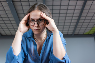 Lonely middle aged woman sitting on bed. Depressed girl at home, looking away with sad expression.