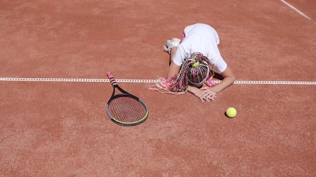 Little girl tennis player crying on the tennis court.