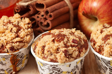 Muffins with apples and cinnamon on wooden background
