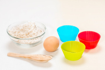 Ingredients for making biscuits: flour, egg, wooden spoon, silicone molds