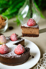 Mousse chocolate cake with strawberry and icing powder sugar. set on cafe table.