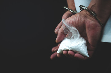 drug addict in handcuffs with a package of drugs in his hands