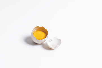 A broken chicken egg on a white background. The yolk is in the shell. The ingredients for the omelet. Farm eggs. Eggs are light in color.