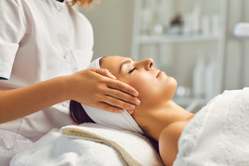 Obraz na płótnie Canvas Spa facial massage. Beautician makes face massage to woman in white beauty salon
