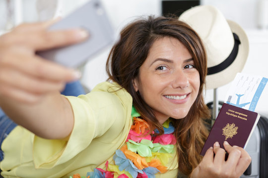 woman taking selfie holding passport and boarding passes
