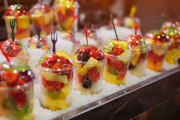 Plastic cups with fresh different fruits on the market.