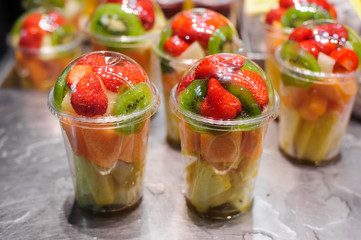 Plastic cups with fresh different fruits on the market.