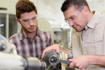 men mending a machine with goggles on