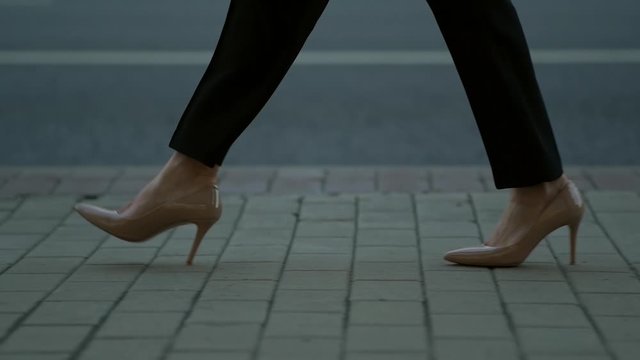 businesswoman is walking in city street, closeup of her feet shod in classic pumps with heels