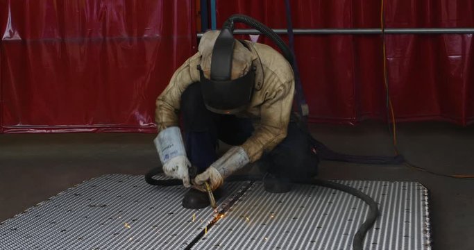 Person with safety cloth holding welding torch and welding metal