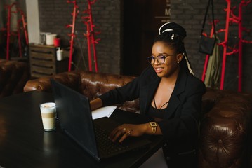 Young African American woman siting at cafe working on laptop