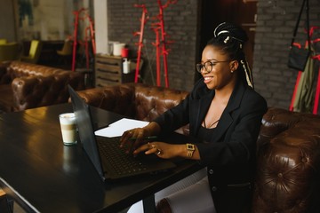 Portrait of a young black woman smiling and using laptop