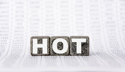 three stone cubes on the background of white financial statements, tables with the word hot. Strong business concept