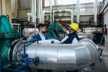 worker in protective equipment and businessman working indoor in industry plant