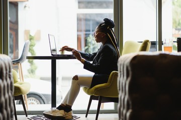Young African American woman siting at cafe working on laptop