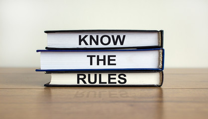 Books with text 'know the rules' on beautiful wooden table. White background. Business concept. Copy space.