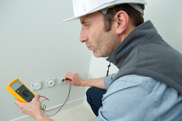 electrician testing electric socket with multimeter